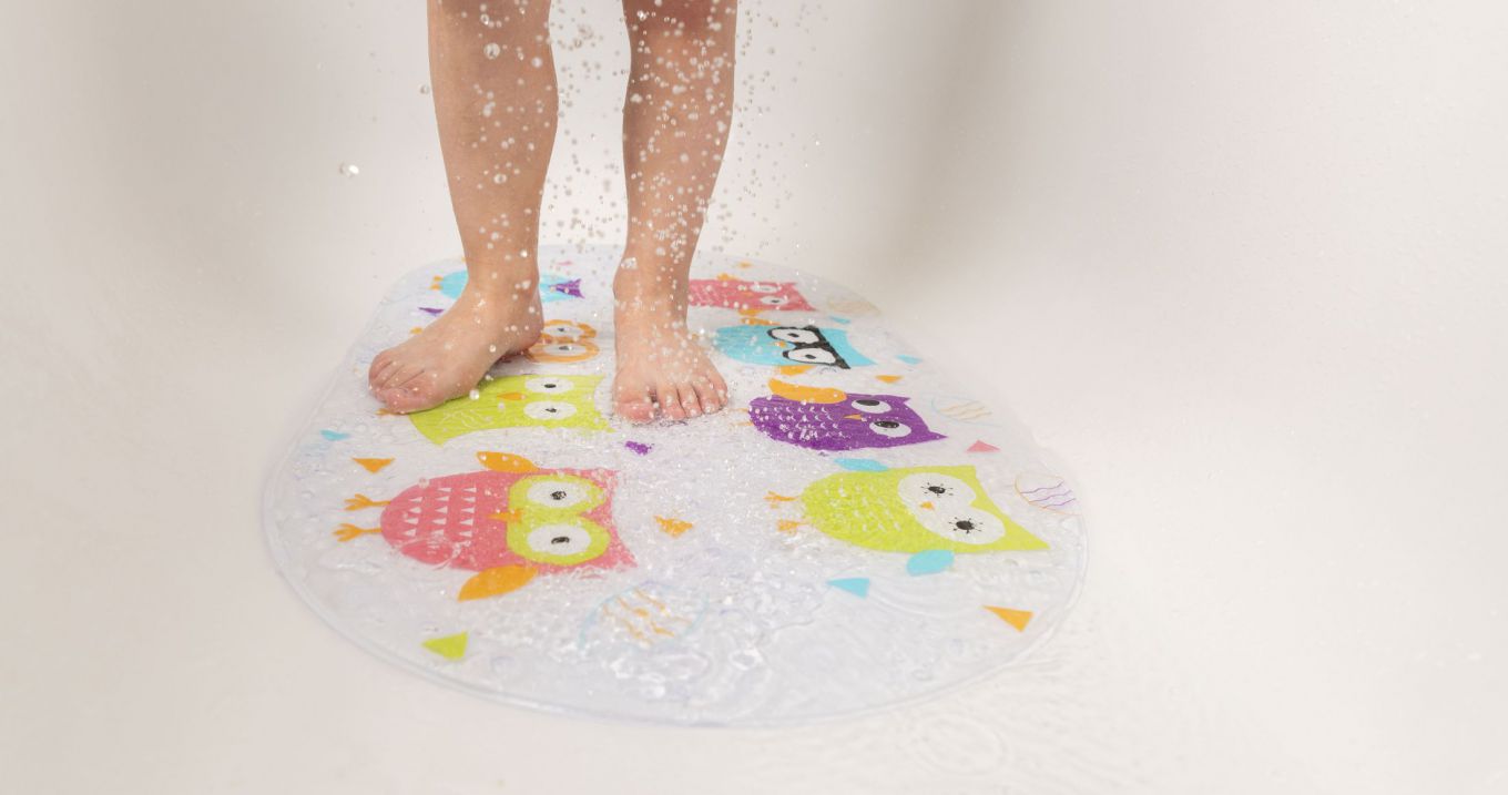 Foto van de onderbenen van een kind op een antislipmat in de douche of badkuip