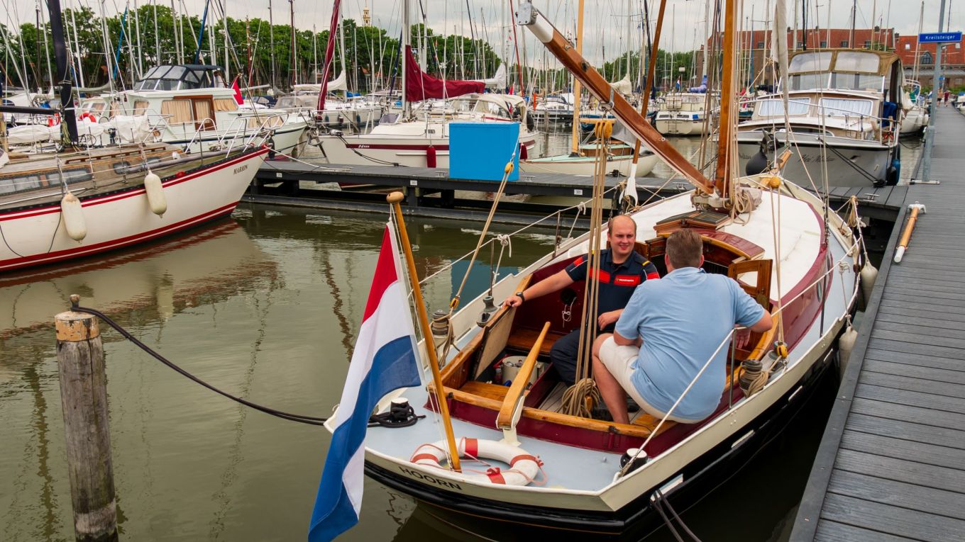 Brandweerman die een gratis botencheck uitvoert bij een man op een boot.