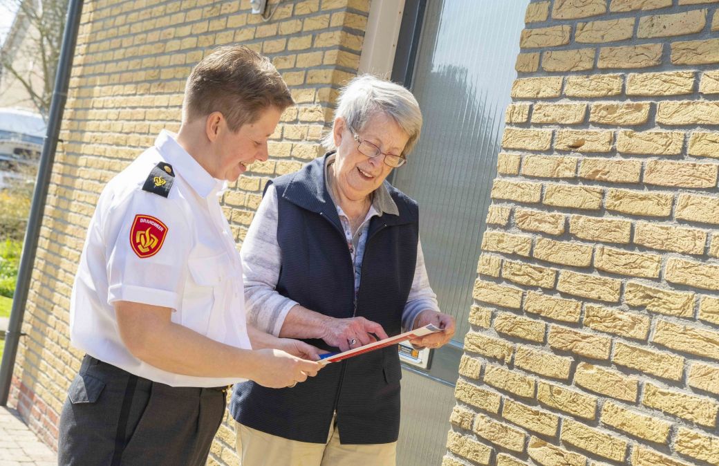Brandweervrouw en bewoner bekijken samen de woningchecklist