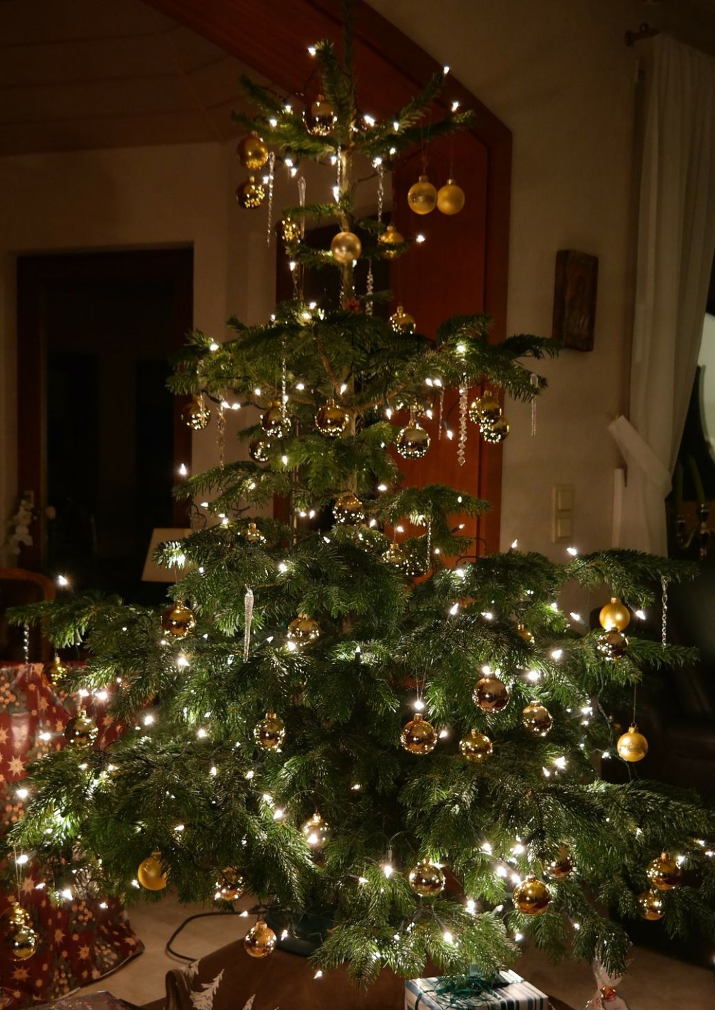 Kerstboom met lichtjes en versiering en cadeautjes op de grond